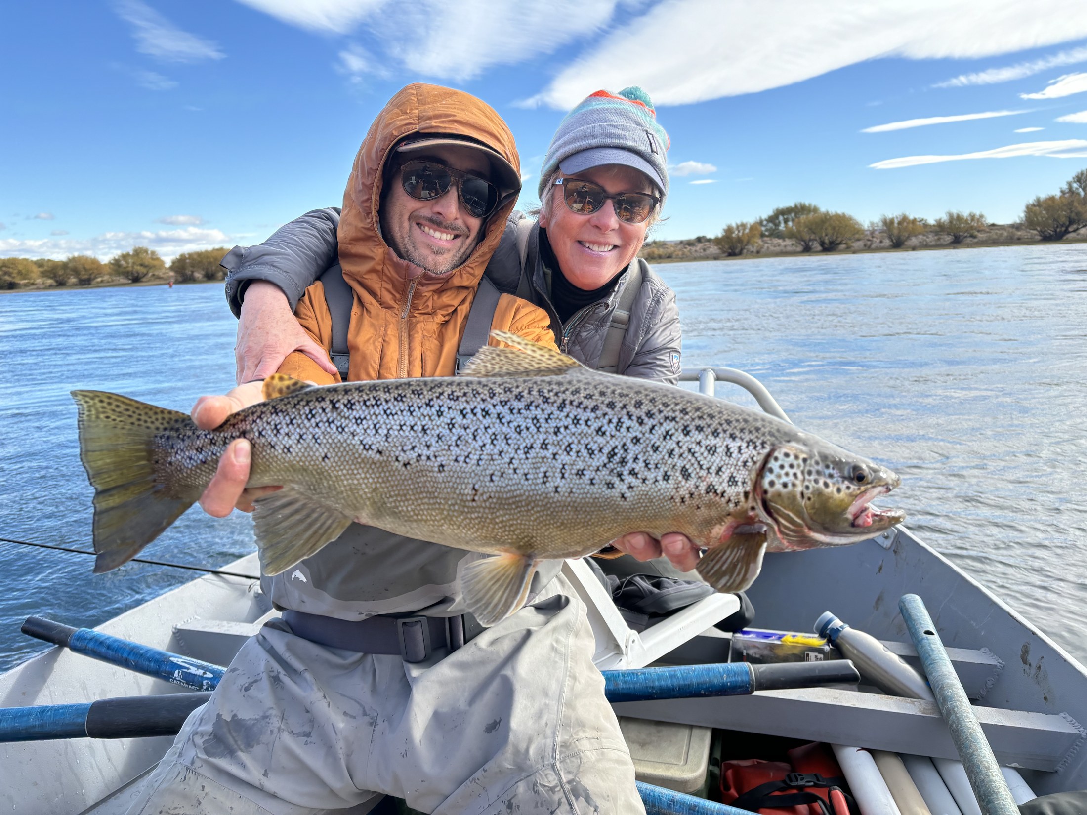 Dos pescadores con una trucha marrón en el bote
