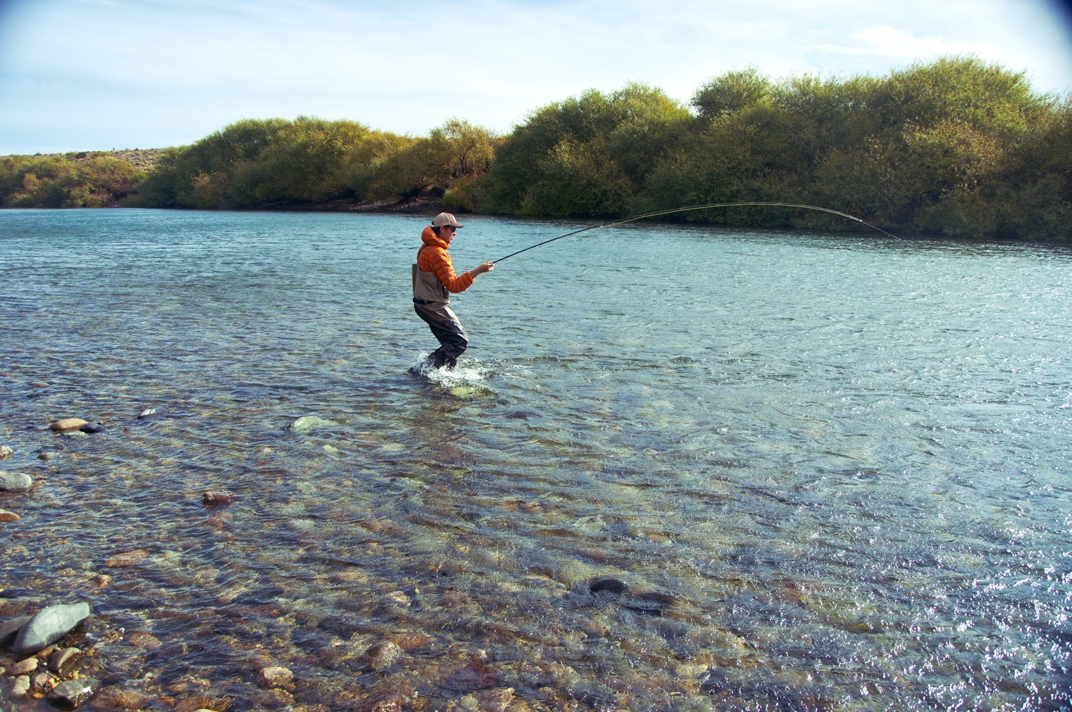 Pescador de vadeo con la caña flexionada en el río