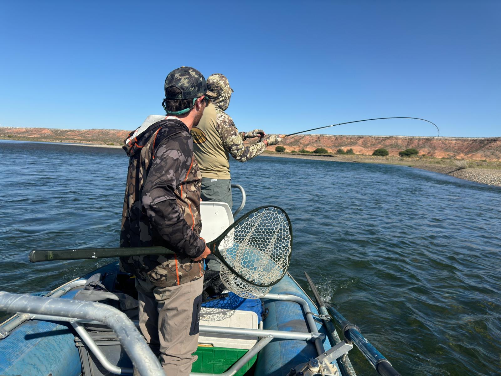 Pescador peleando un pez desde el bote y guía con el copo