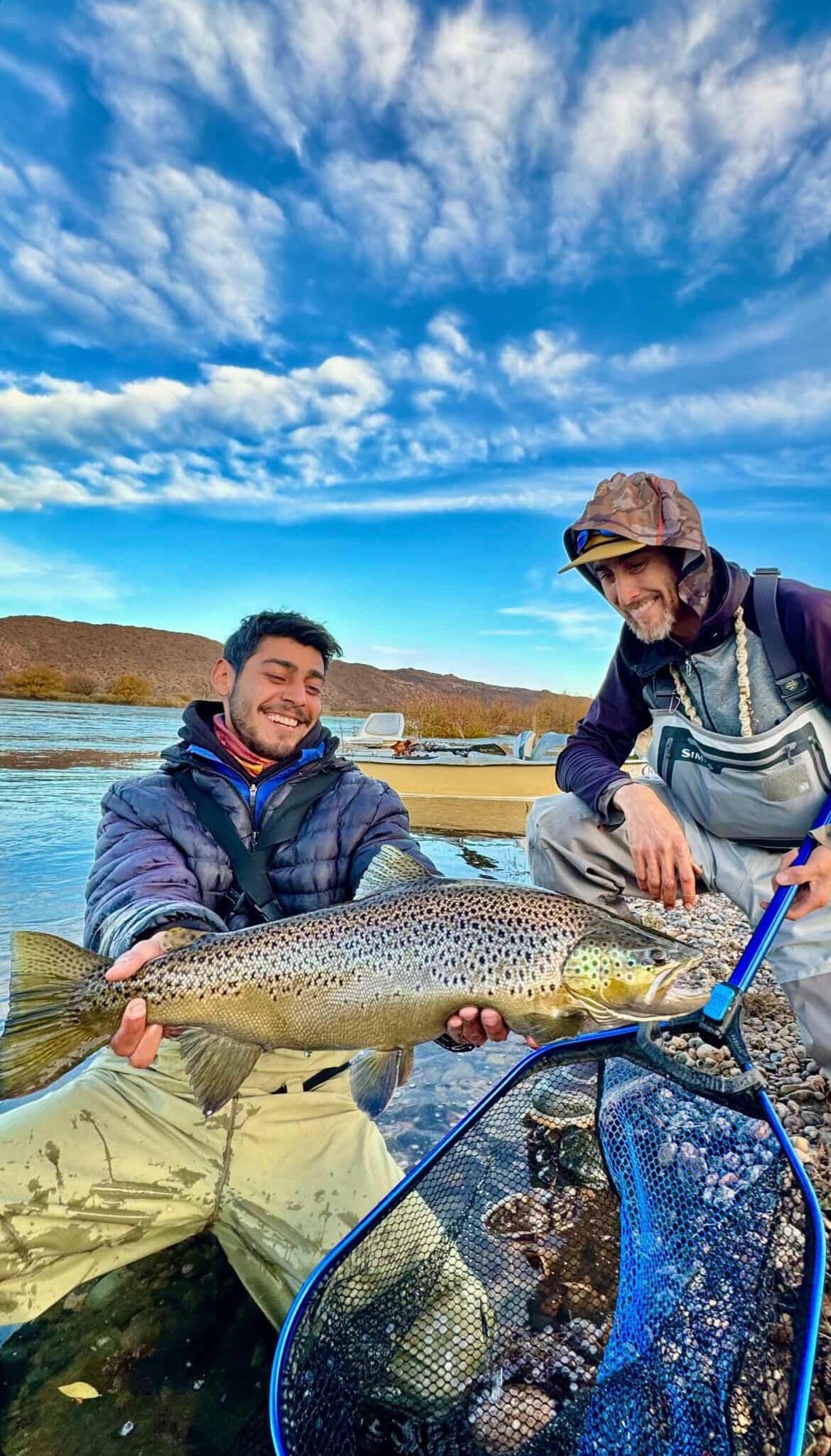 Pescadores con una trucha en un bote
